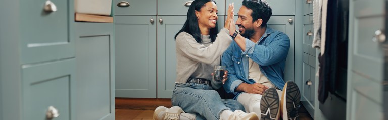 A husband and wife share coffee and connection on their kitchen floor—a moment of warmth, communication, and love in everyday married life.